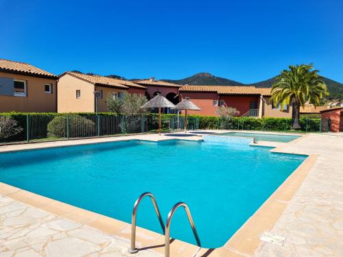 - une piscine dans une cour avec des maisons et des arbres dans l'établissement 3 pièces entre mer et nature - Les Clés de l'Esterel, à Théoule-sur-Mer