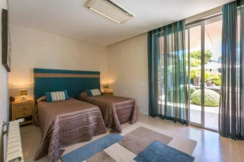 una camera da letto con due letti e una grande finestra di Villa Atlantic Pearl - Luxury villa located in a Quinta do Lago