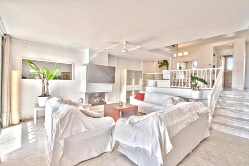 a living room with white furniture and a staircase at Club Villamar - Sereni in Sant Feliu de Guíxols