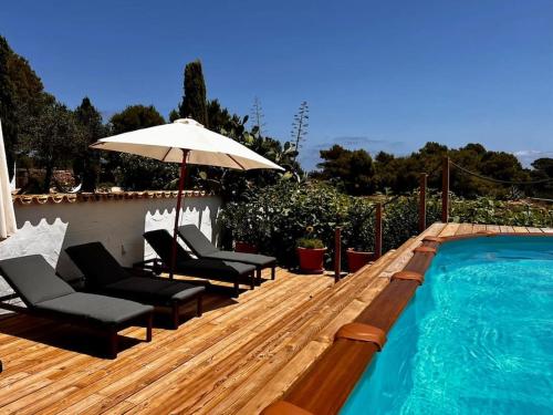 een houten terras met stoelen en een parasol naast een zwembad bij Home / Rural Modern House in Sant Ferran de Ses Roques