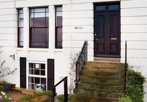 a black door on a white house with stairs at Crescent View - Panoramic sea views in Filey