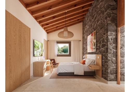 a bedroom with a bed and a stone wall at Reverence Villas Caldelas in Antas de Ulla