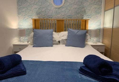 Un dormitorio con una cama grande con almohadas azules. en Apartment 2, 11 The Beach - Ground floor beachfront apartment - Ocholo Villas, en Filey