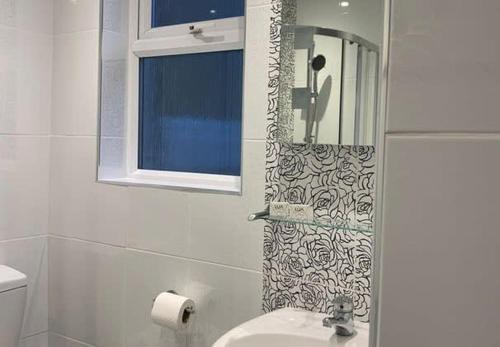 Un baño con cortina de ducha y lavabo. en Apartment 2, 11 The Beach - Ground floor beachfront apartment - Ocholo Villas, en Filey
