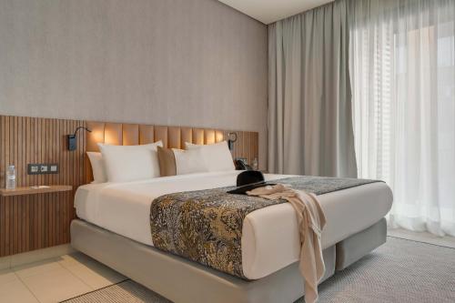 un dormitorio con una cama grande con un gato sentado en ella en Pestana Casablanca, Seaside Suites & Residences en Casablanca