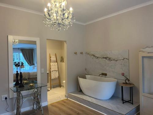 a bathroom with a large white tub and a chandelier at The Dunes Resort - Forest View in Plettenberg Bay
