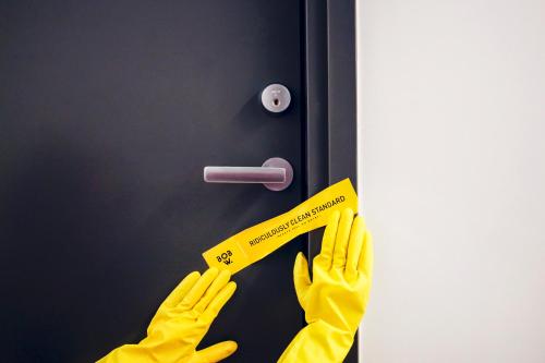 a person wearing yellow gloves holding a door handle at Bob W Peterhof in Freising
