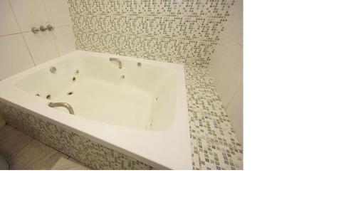 a white bath tub in a bathroom with a tile wall at Minuty Motel Itu in Itu