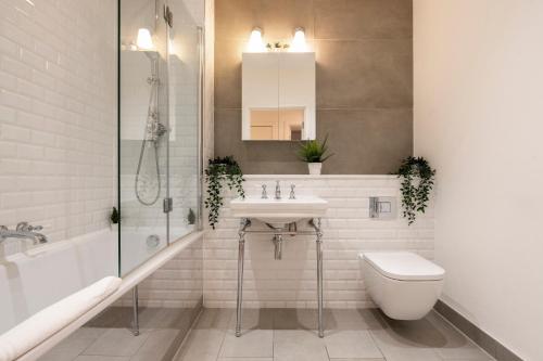a white bathroom with a sink and a toilet at Camden Town Apartments in London