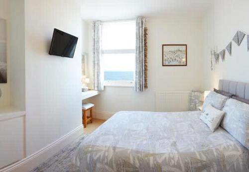 Una habitación blanca con una cama y una ventana en Apartment 17, The Moorings - Stunning sea views, en Filey