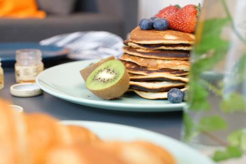 Een bord met een stapel pannenkoeken en fruit op een tafel. bij Apartament Loftowy na Spokojnej in Kołobrzeg