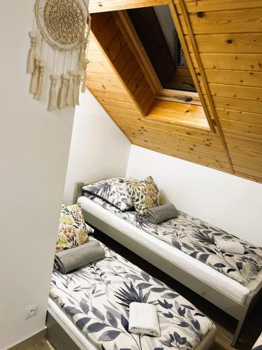 two beds in a room with a wooden ceiling at Pokoje Gościnne Malinówka in Krościenko