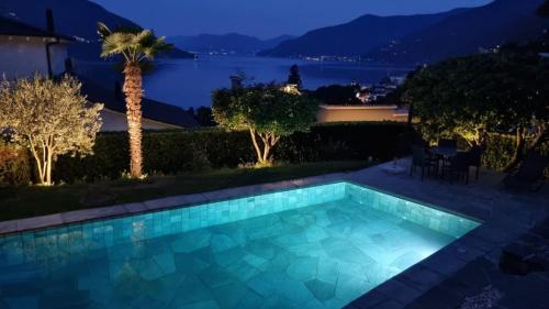 a swimming pool with a view of the water at night at Casa Ramerino in Brissago
