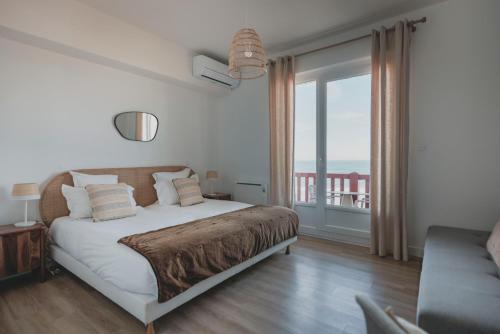 a bedroom with a bed and a large window at Hôtel de La Plage in Hossegor