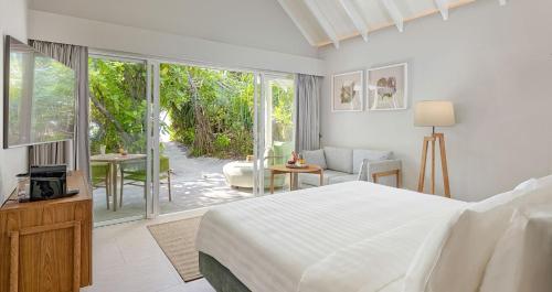a white bedroom with a bed and a patio at RAAYA By Atmosphere - Premium All Inclusive with Free Transfers in Raa Atoll