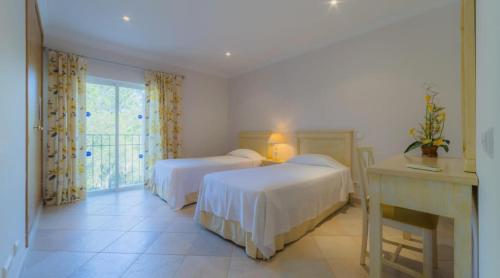 une chambre avec deux lits et un bureau et une fenêtre dans l'établissement Villa Tulipa - luxury golfing resorts, à Almancil