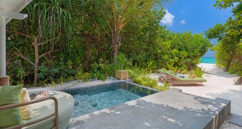 a swimming pool next to a beach with trees at RAAYA By Atmosphere - Premium All Inclusive with Free Transfers in Raa Atoll