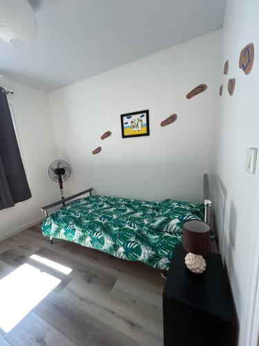 a bedroom with a bed with a green comforter at La Piaule De Nessadiou in Bourail