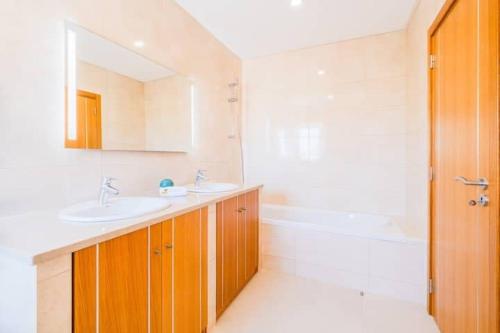 La salle de bains est pourvue de 2 lavabos, d'une baignoire et d'un miroir. dans l'établissement Villa Vida, à Albufeira