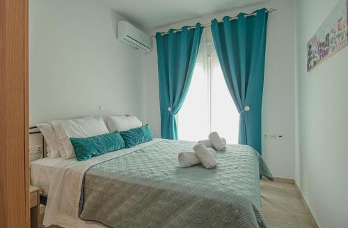 a bedroom with a large bed with blue curtains at Basiliki's Apartments in Archangelos