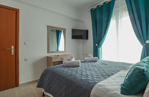 a bedroom with a bed with blue curtains and a window at Basiliki's Apartments in Archangelos