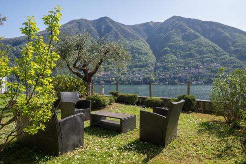 a row of chairs and a table with mountains in the background at [Lake View] Private Covered Parking and Terrace in Carate Urio