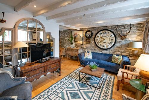 a living room with a large clock on a stone wall at Cosy Little Hyde Cottage, Swanage in Swanage