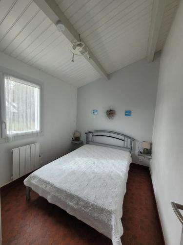 une chambre avec un lit dans une pièce blanche dans l'établissement Dolce Vita, à Notre-Dame-de-Monts