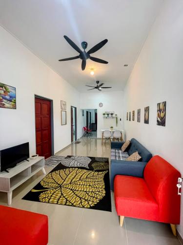 a living room with a red couch and a ceiling fan at Homestay CikguMa - Netflix & Wifi in Kota Bharu