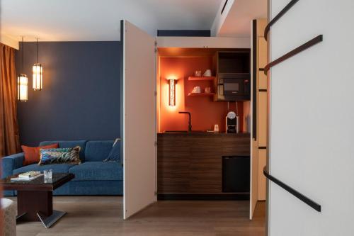 a living room with a blue couch and a kitchen at Hôtel & Spa Oceania Le Conti in Brest