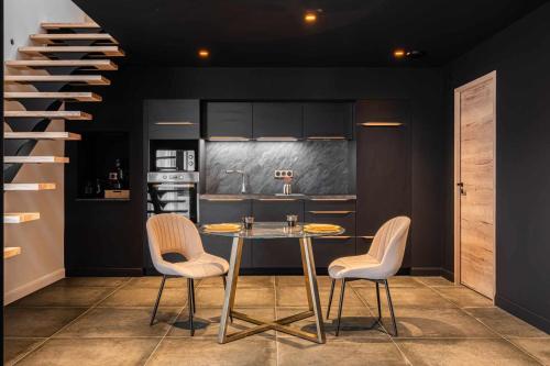 a kitchen with a glass table and two chairs at 7eme loft in Saint-Victor-de-Cessieu