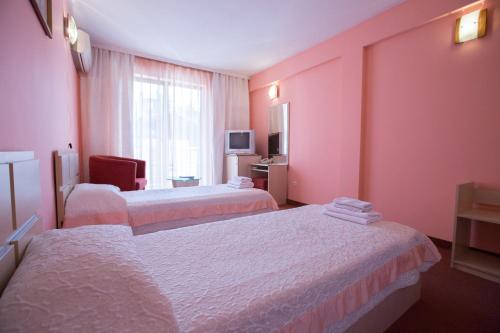 ein Hotelzimmer mit 2 Betten und einem TV in der Unterkunft Семеен Хотел Сокол in Sandanski