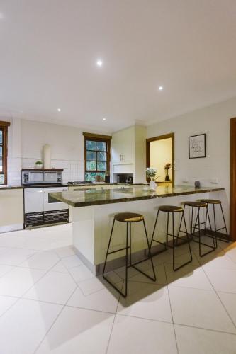 a large kitchen with a large island with bar stools at Hinterland Retreat on 30 acres - Sleeps 6 in Broughton Village