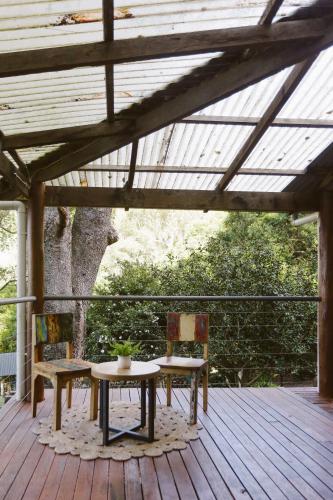 two chairs and a table on a wooden deck at Hinterland Retreat on 30 acres - Sleeps 6 in Broughton Village