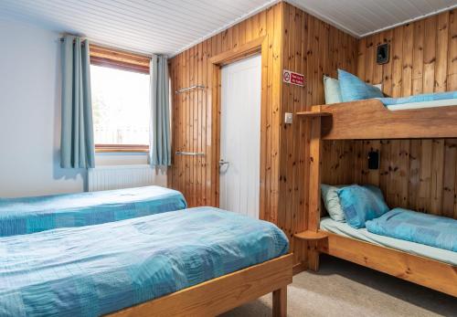 a bedroom with two bunk beds and a window at Insh Hall Rooms at Loch Insh in Kincraig