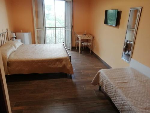 um quarto com duas camas e uma mesa e uma janela em Casa Chiara em Scilla