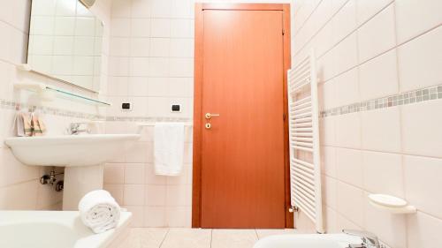 a bathroom with a sink and a toilet and a door at Le Due Farfalle by Ca-Sa Check in Chioggia