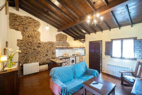 sala de estar con sofá azul y pared de piedra en La Casona Del Cura I en Pravia