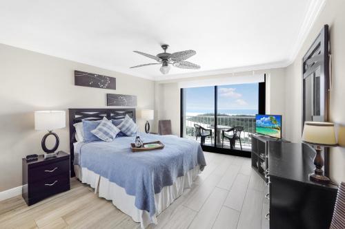 a bedroom with a bed and a tv and a balcony at South Seas Tower 4-704 in Marco Island