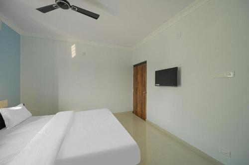 a bedroom with a white bed and a flat screen tv at Hotel Grace Premium Bhubaneswar in Bhubaneshwar