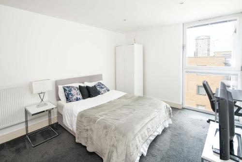 a white bedroom with a bed and a desk with a computer at Immaculate 1-Bed Apartment in London in London