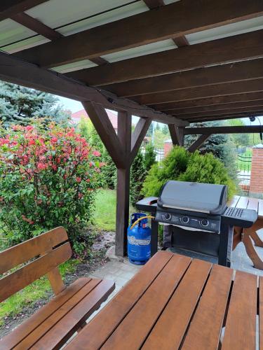 a picnic table and a grill under a wooden pergola at Lwi dworek LD in Jarosław