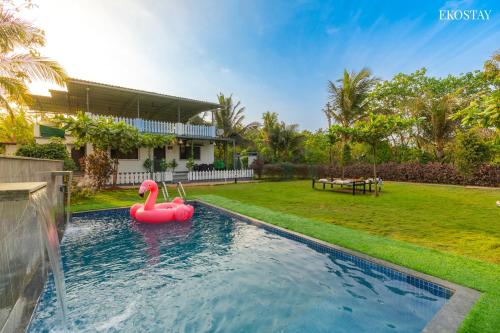 a pool with a pink inflatable flamingo in a yard at EKO STAY- PANORAMA VILLA in Alibaug