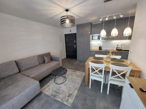 a living room with a couch and a table at Apartamenty Słoneczne Balkony in Sarbinowo