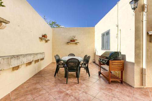 a patio with a table and chairs and a grill at A Lovely 3BR Maisonette in lovely town of Rabat by 360 Estates in Busugrilla