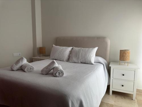 a white bed with three pillows on top of it at Apartamento céntrico con terraza in Córdoba