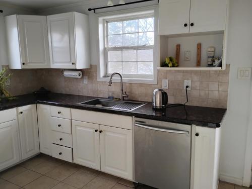 a kitchen with white cabinets and a sink and a window at Bluenose Bed and Breakfast in Halifax
