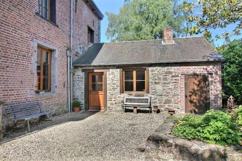 a brick house with a bench in front of it at Château de Rienne met sauna & hottub & pooltafel in Gedinne