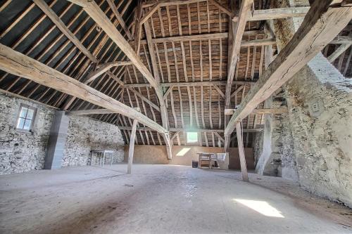 an empty room in an old barn with wooden ceilings at Château de Rienne met sauna & hottub & pooltafel in Gedinne