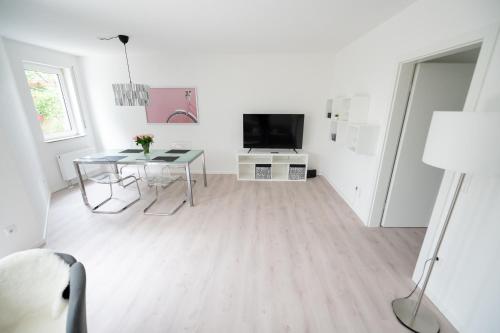 een witte woonkamer met een tafel en een televisie bij Ferienwohnung Gilla in Leopoldshöhe